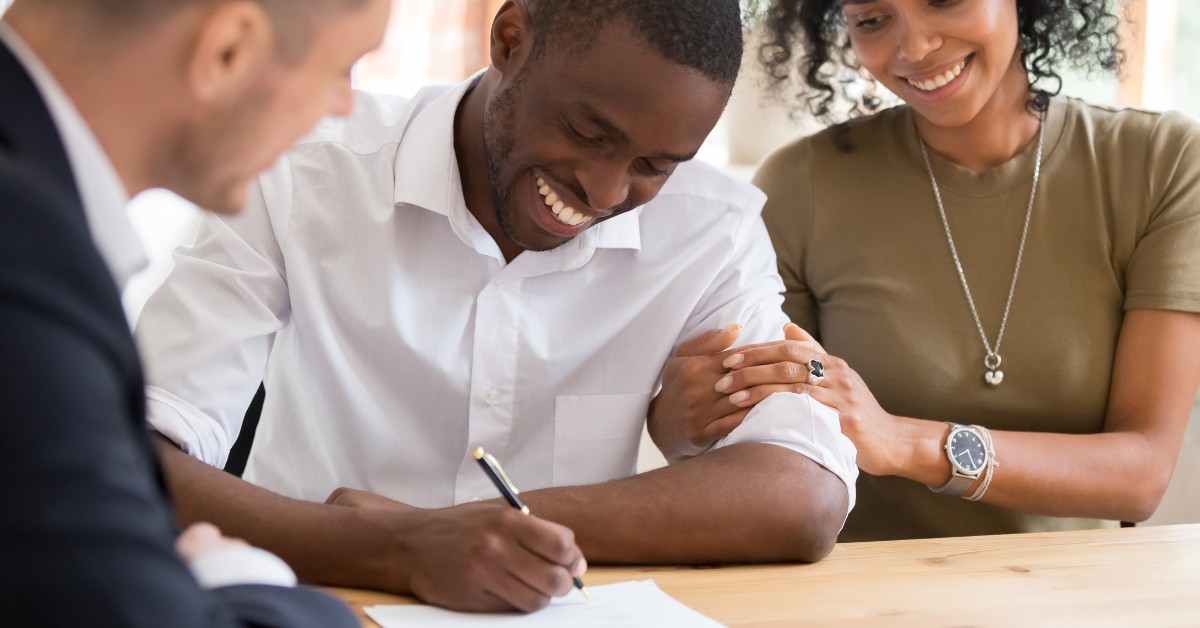 a group of people smiling and looking at a paper