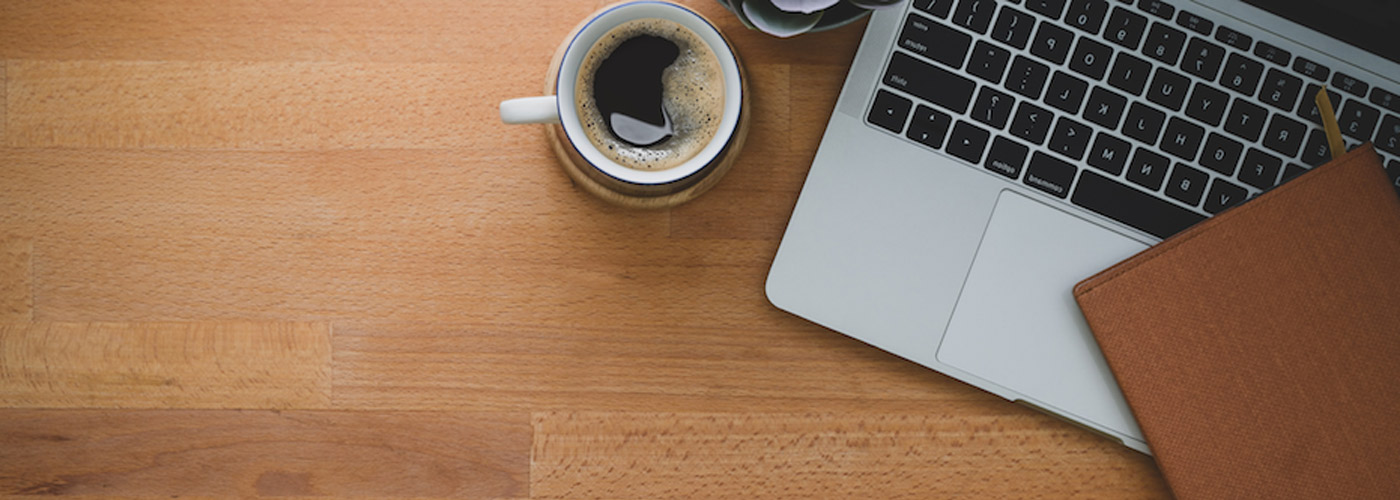 Overhead shot of a laptop and coffee mug on a desk